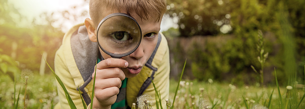 A little boy holding a magnifying glass.